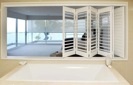 A stylish bathroom featuring white multi-fold plantation shutters Adelaide by ASI Security, offering privacy and a bright, open feel.